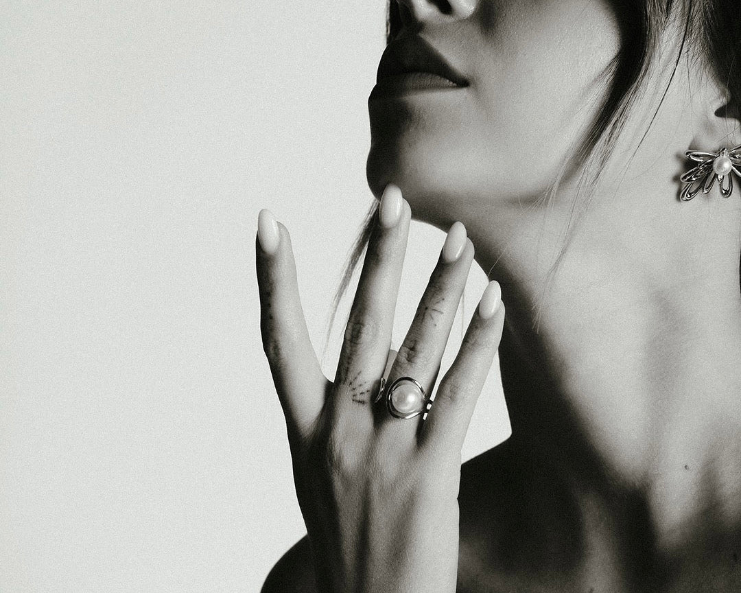 Immagine in bianco e nero di donna con top nero che mostra anelli sovrapposti Medema collezione Atene su più dita, guida di stile dal giorno alla sera