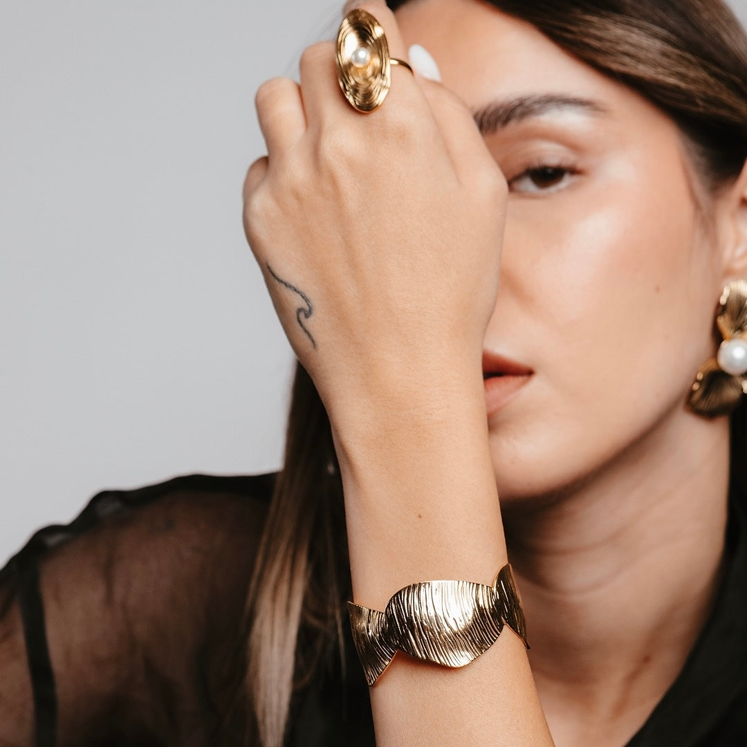 Translation missing: it.Modella indossa anello e bracciale dorati Collezione Cairo, gioielli scultorei ispirati alle dune del deserto: Cairo