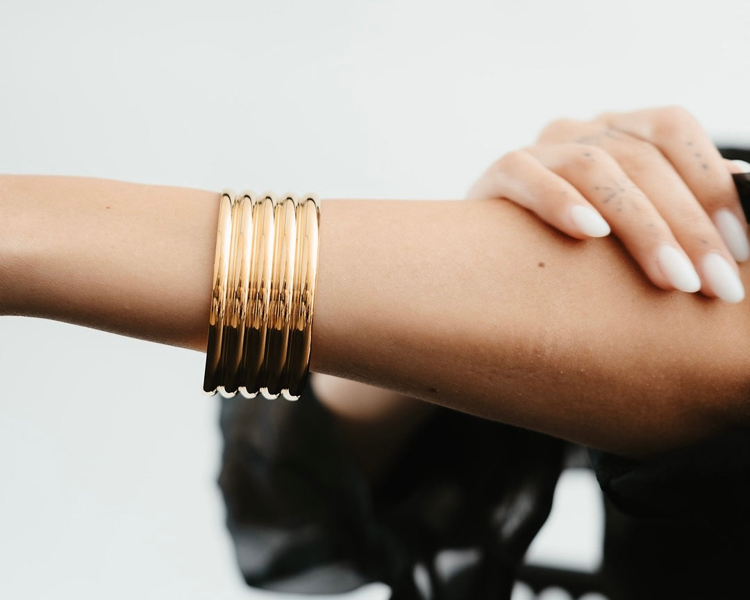 Translation missing: it.Donna che indossa braccialei rigido dorati Medema al polso, gioielli eleganti in acciaio inossidabile placcato oro 18 carati con texture ondulata: Bracciali