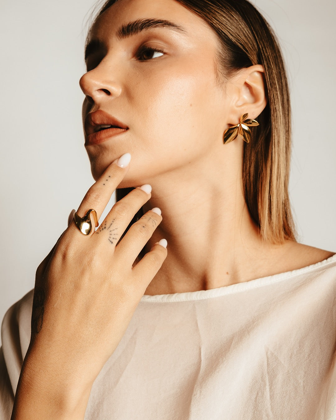 Dettaglio orecchini dorati Medema a forma di foglia con superficie lucida a specchio