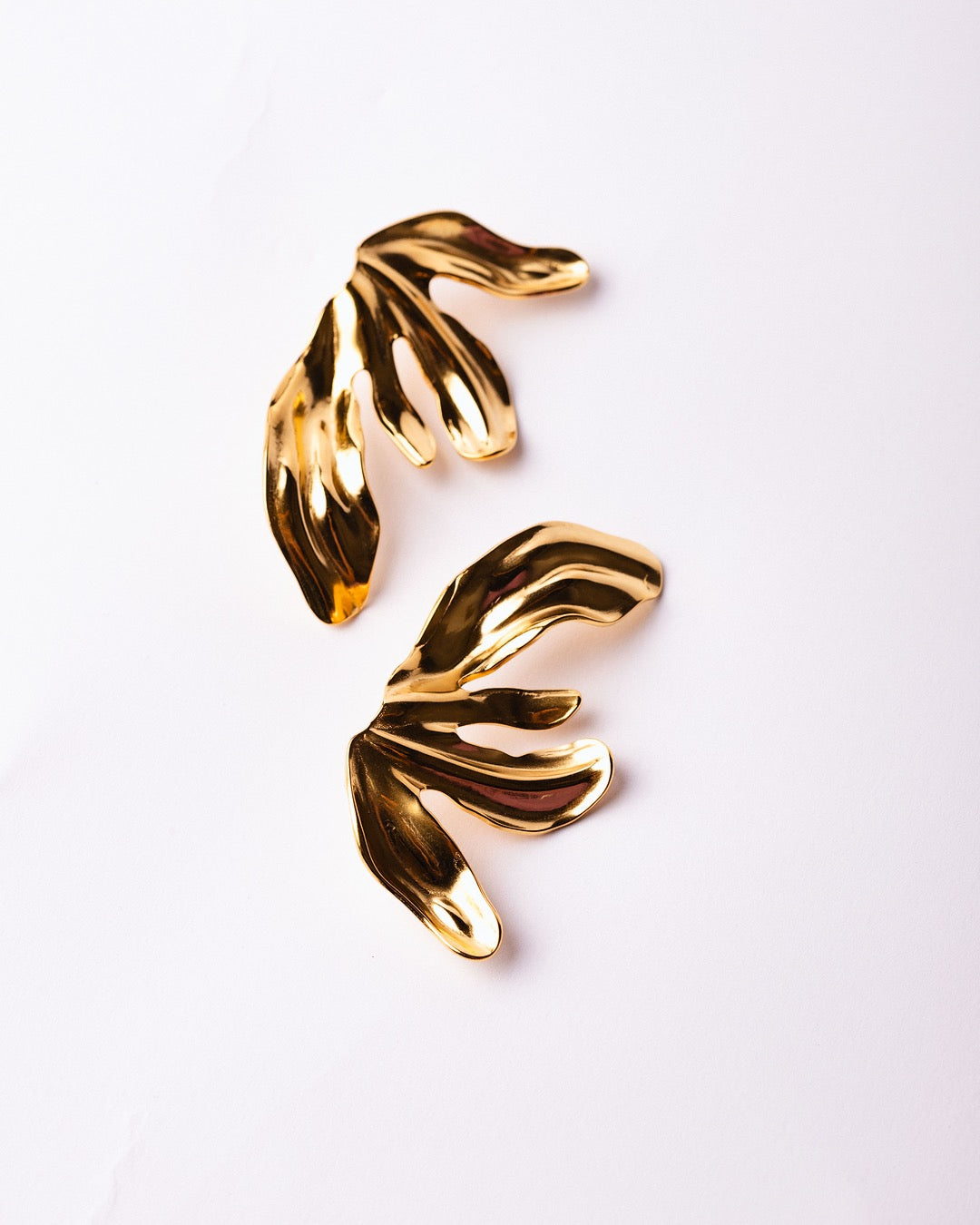 Orecchini Medema Cairo Foglia Scultorea su sfondo grigio chiaro, luce calda e finitura lucida