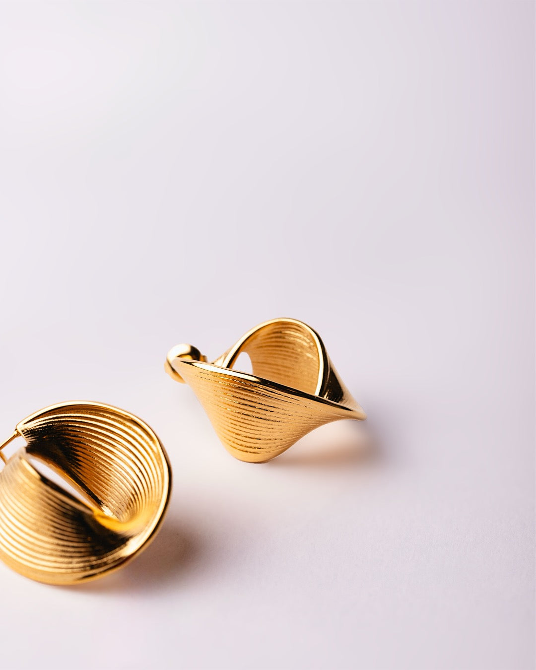 Orecchini Cairo Avvolgenti su sfondo bianco, linee intrecciate e design scultoreo