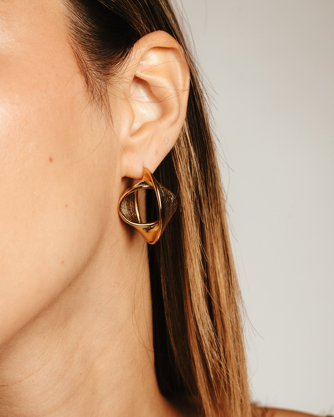 Primo piano laterale della modella con gli orecchini Medema, riflessi dorati sofisticati