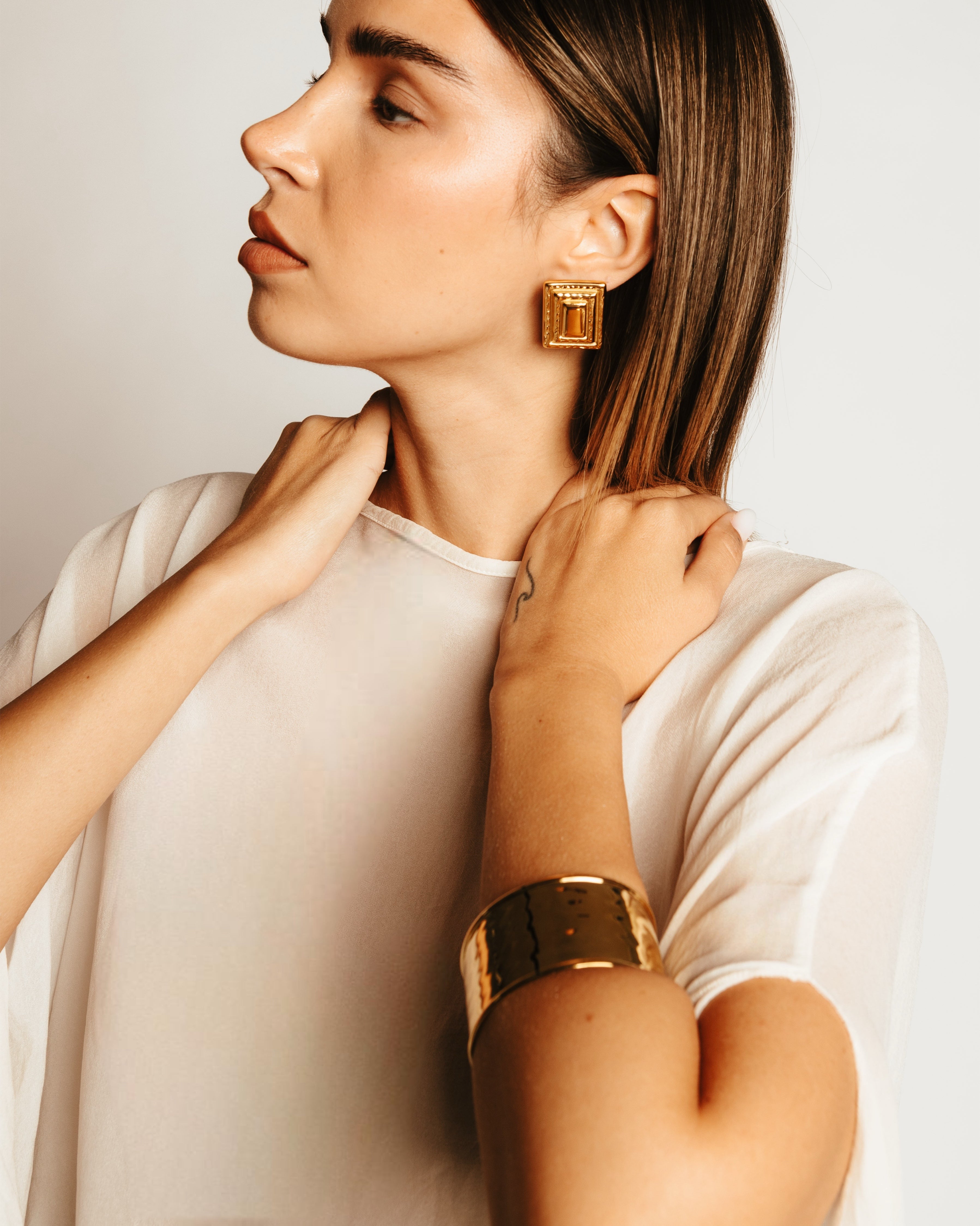 Vista laterale della modella con Bracciale dorato Medema, design ampio e finitura a specchio