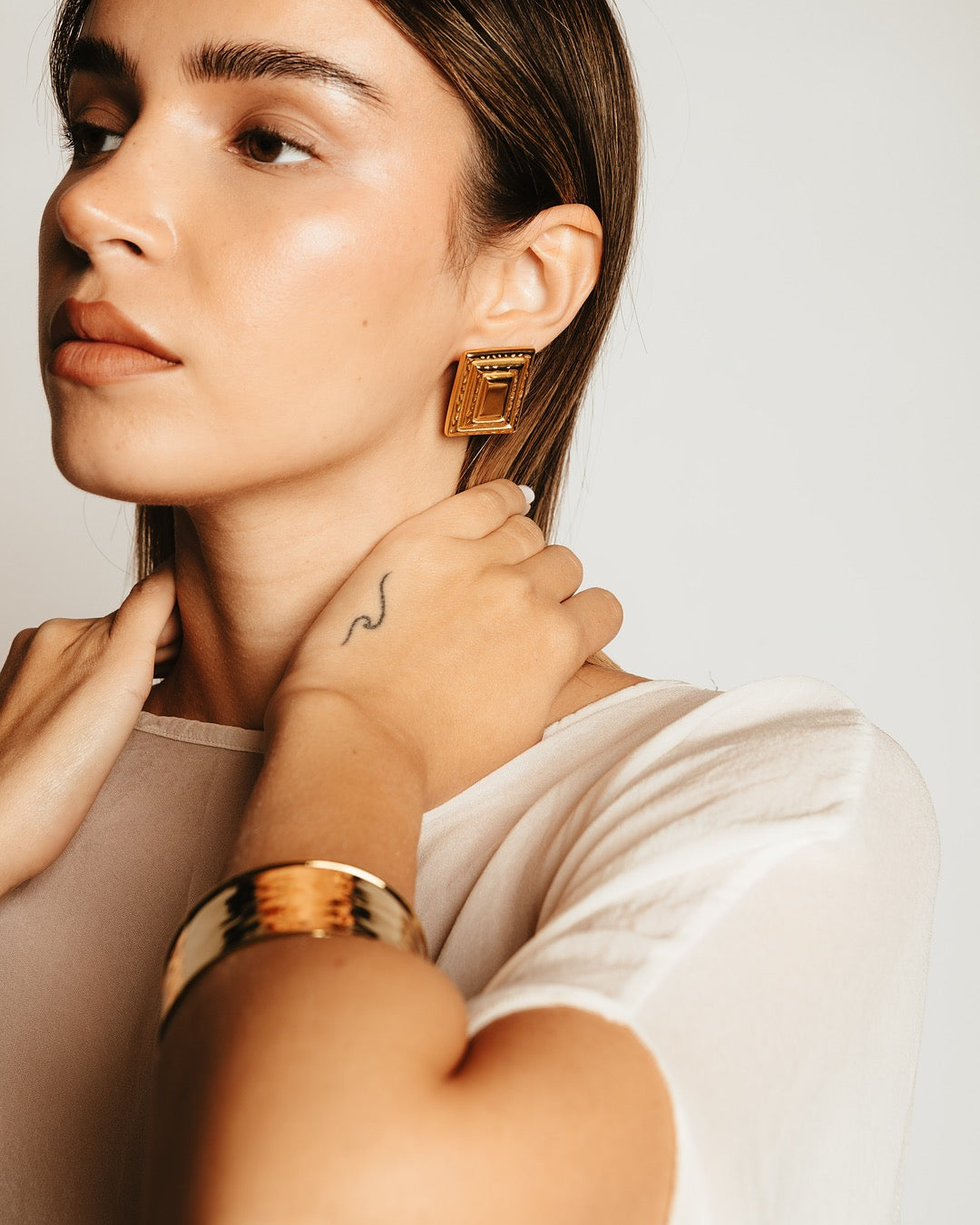 Primo piano laterale della modella con Orecchini dorati Medema, ispirati all’arte e all’architettura classica