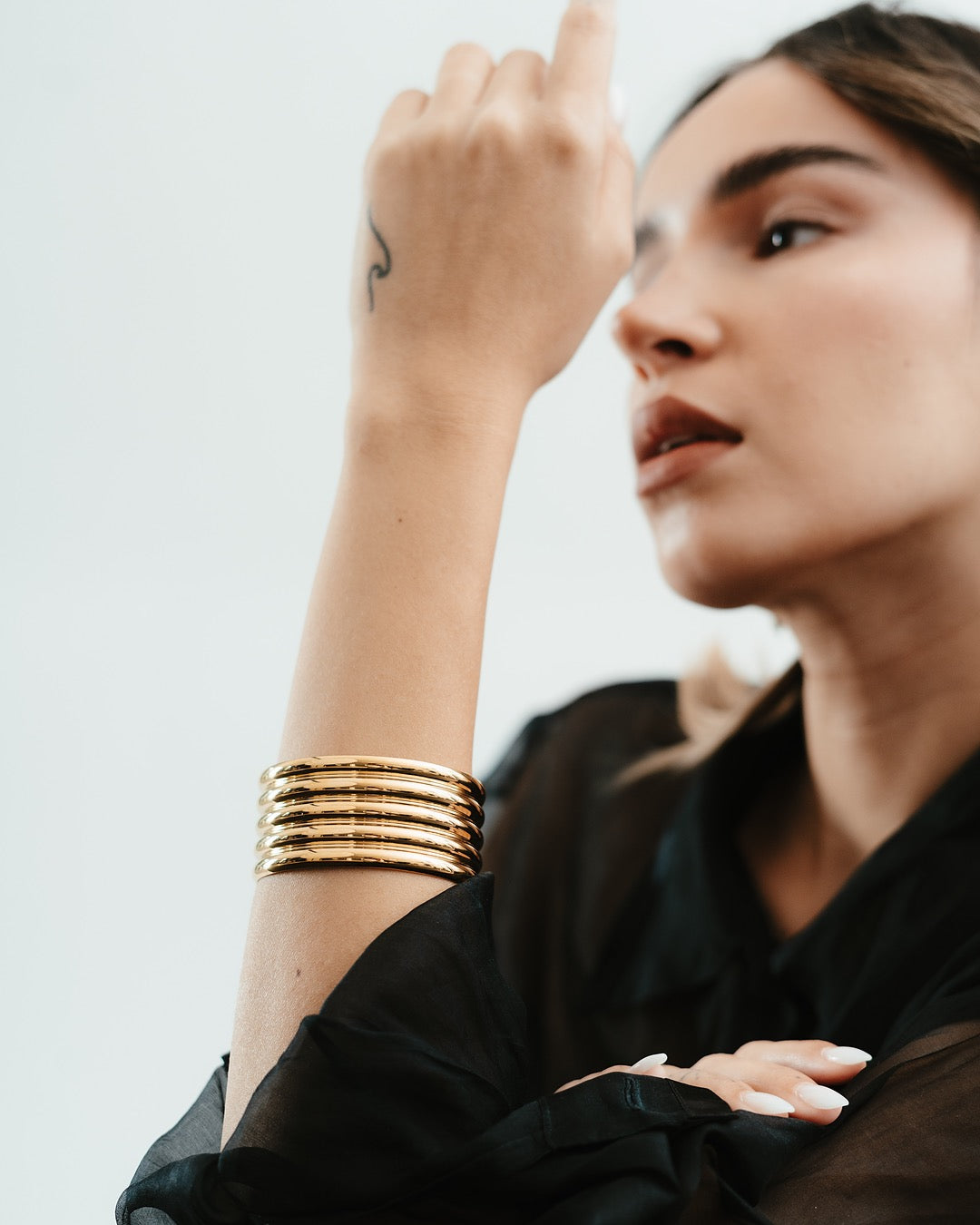 Vista laterale della modella con Bracciale Medema Roma Colonne Dorate, fascino deciso e moderno