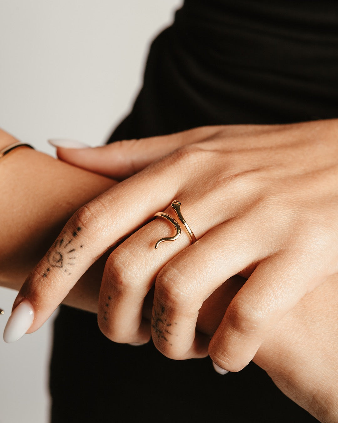 Dettaglio mano femminile con anello serpente dorato e occhi verdi Medema