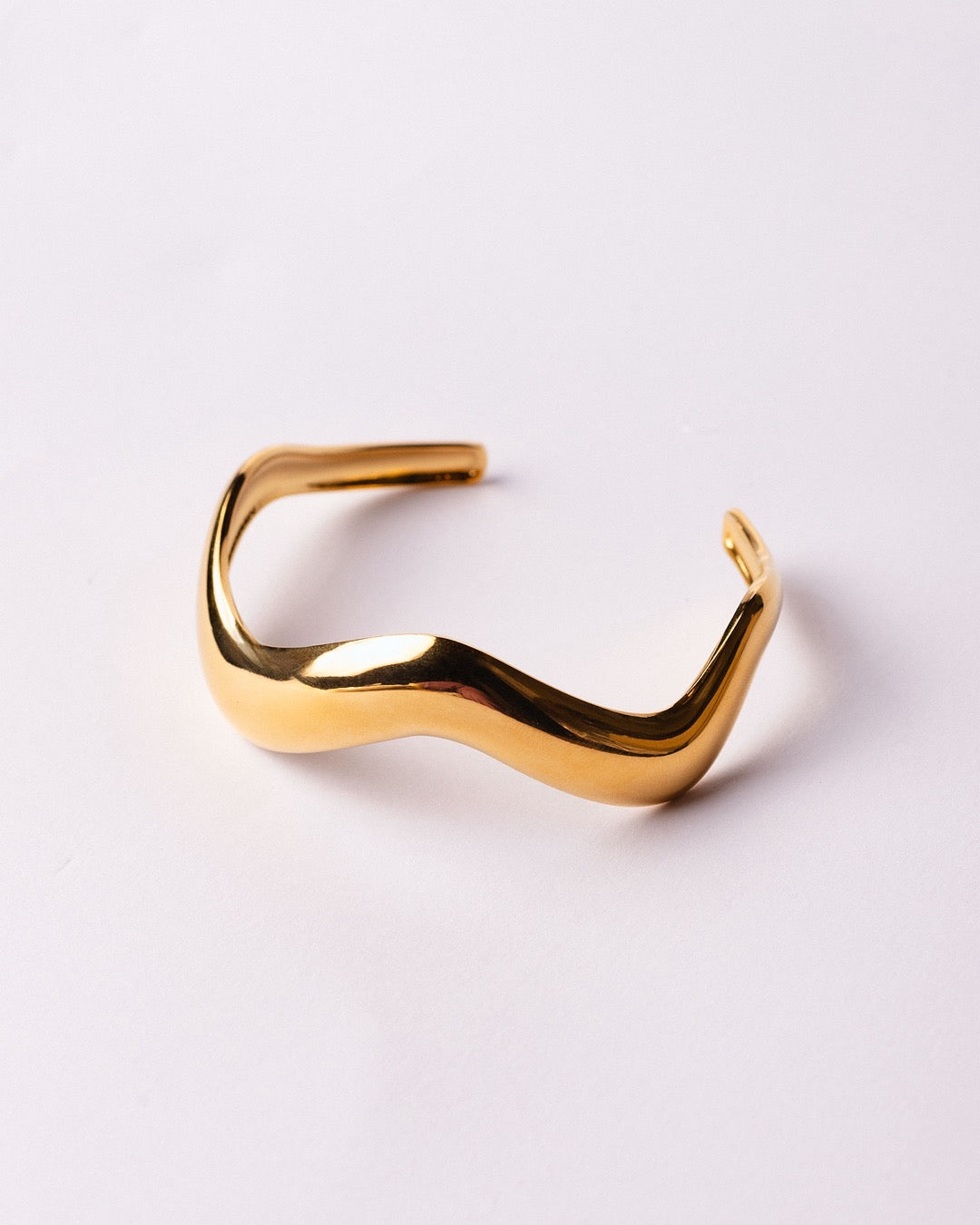 Vista laterale del Bracciale dorato Medema, finitura lucida che riflette la luce con eleganza scultorea