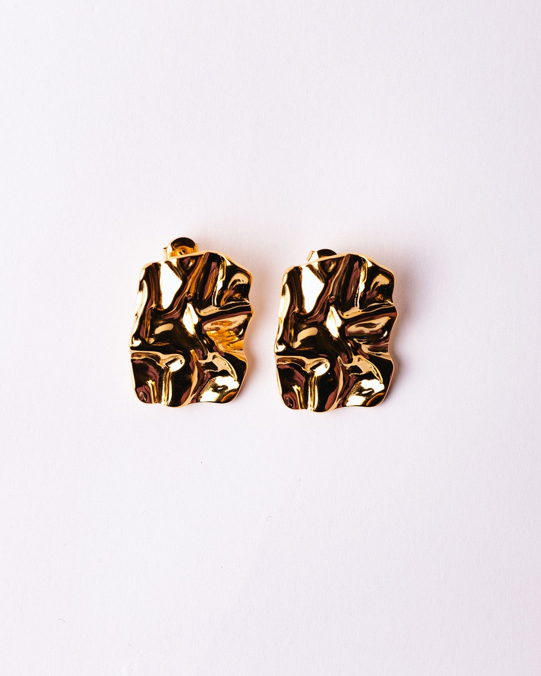 Dettaglio orecchini dorati Medema in acciaio placcato oro 18K, superficie scolpita e brillante