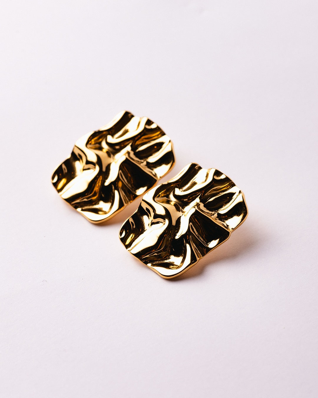 Orecchini Firenze Forma Scultorea Medema fotografati su fondo neutro, riflessi dorati e linee fluide