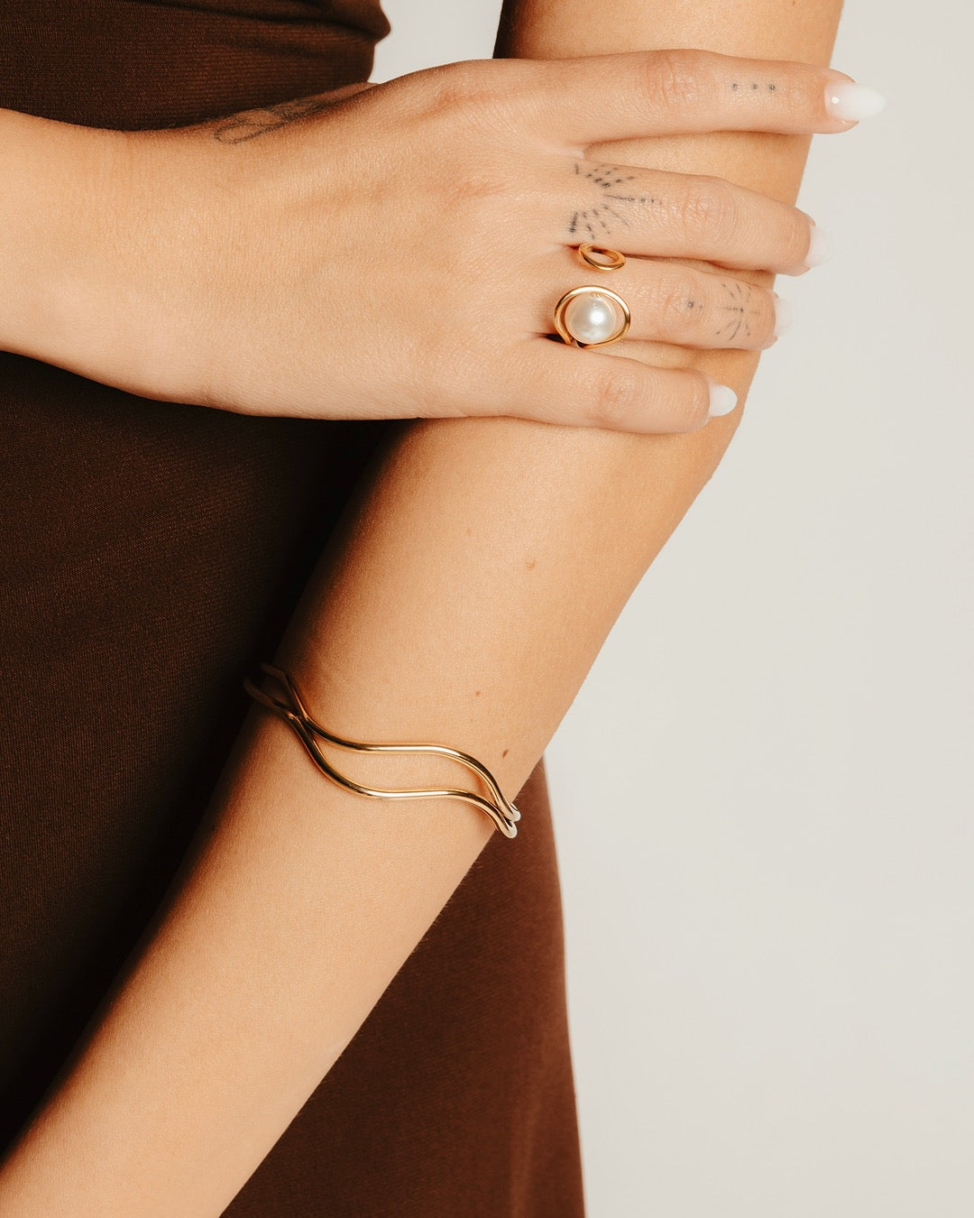 Bracciale Cairo Doppia Onda Medema indossato con altri accessori dorati, stile raffinato e contemporaneo