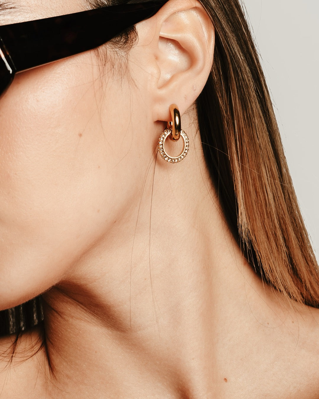 Primo piano della modella con Orecchini dorati Medema, cerchi intrecciati che riflettono luce e raffinatezza