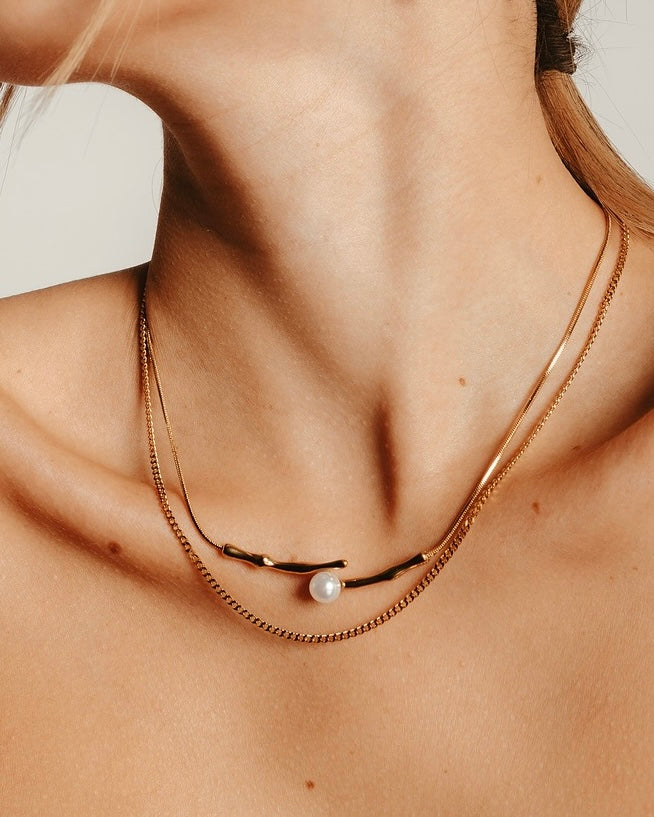 Primo piano del collo con Collana Medema Atene Ramo di Luce, doppia catena dorata e perla centrale