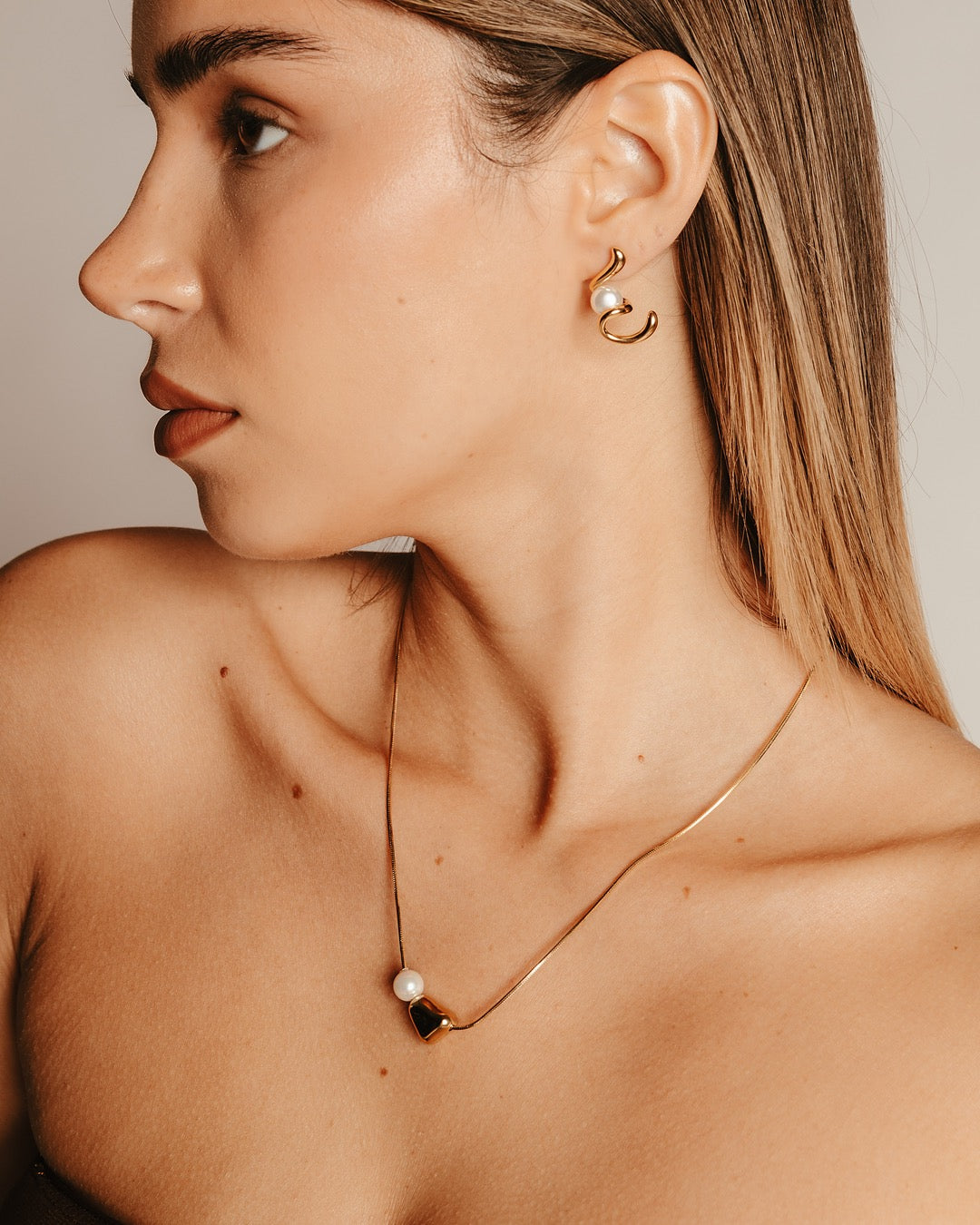 Modella con Collana Medema Atene, equilibrio tra perla e forma scultorea dorata