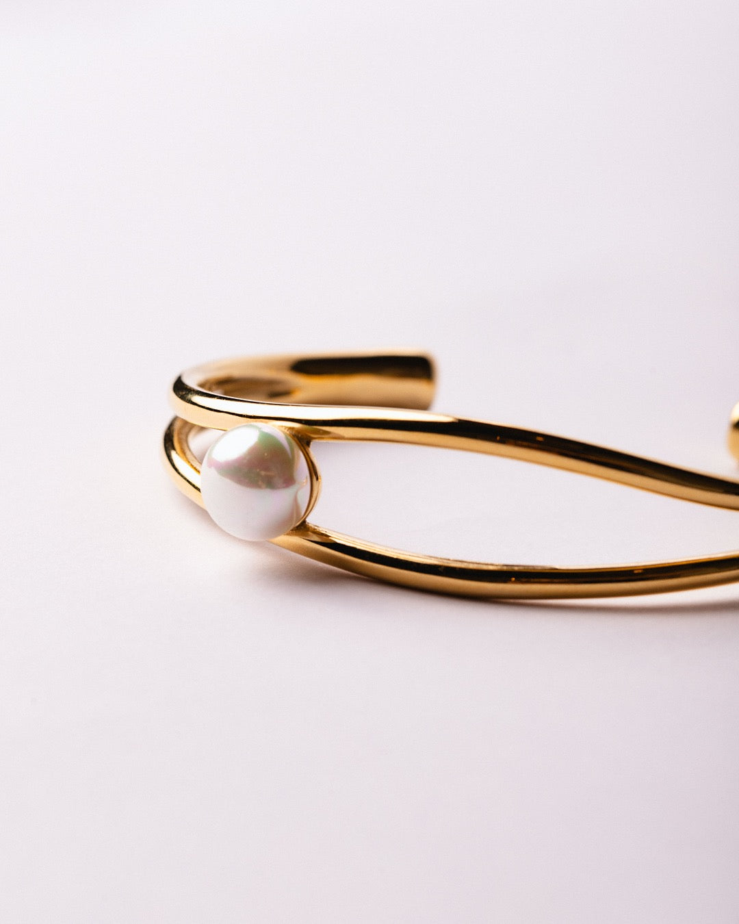 Bracciale Medema Atene dorato su sfondo chiaro, perla incastonata e design elegante