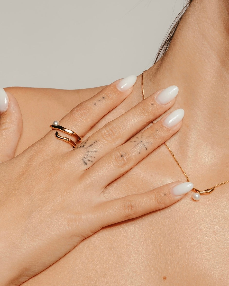 Primo piano della mano con Anello Medema Atene Onde Dorate, riflessi dorati e luce calda