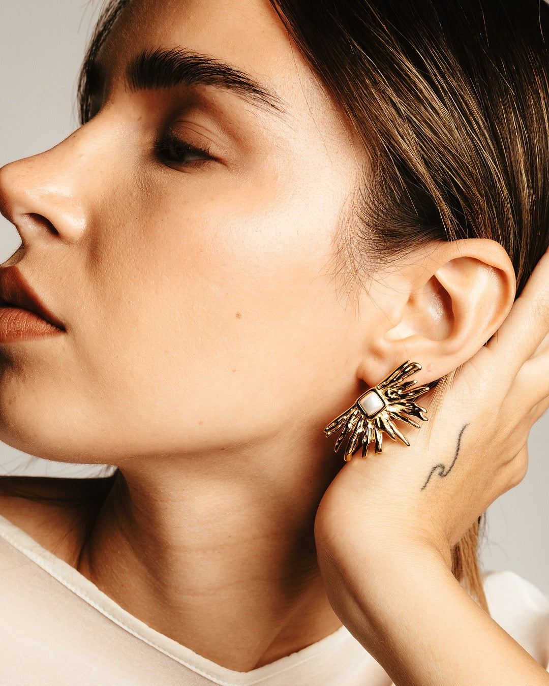 Primo piano laterale della modella con Orecchini Medema Atene Fiamma Dorata, luce dorata e stile raffinato