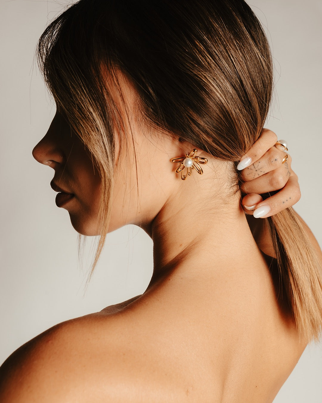 Modella indossa gli Orecchini Atene Fiore Dorato Medema, eleganza raffinata e luce dorata