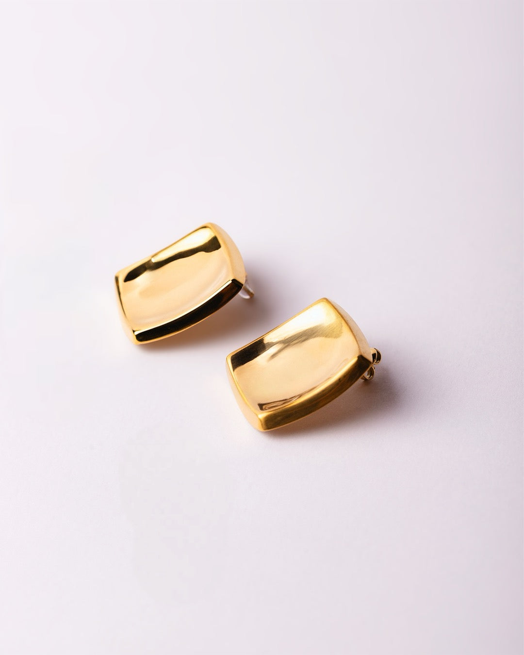 Orecchini quadrati Medema Copenhagen su fondo chiaro, stile minimal e riflessi luminosi